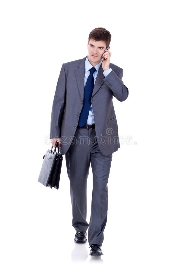 a man in a suit and tie talking on his cell phone while holding a briefcase