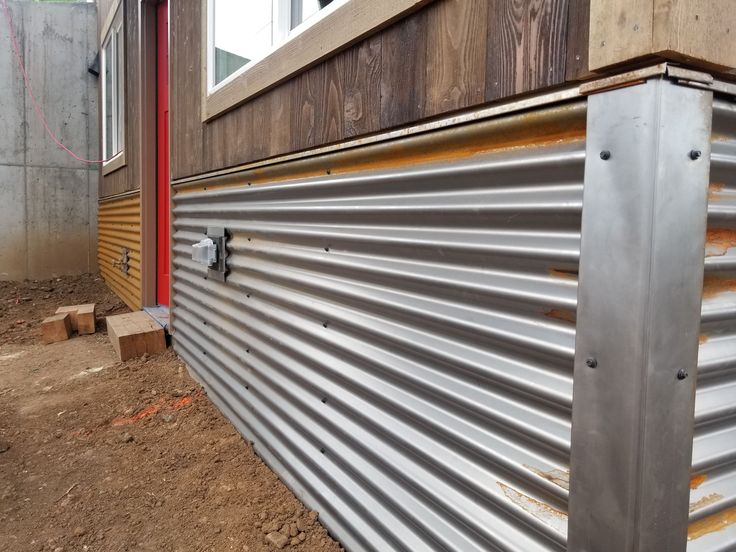 the side of a building that is being built with metal siding and wood slats