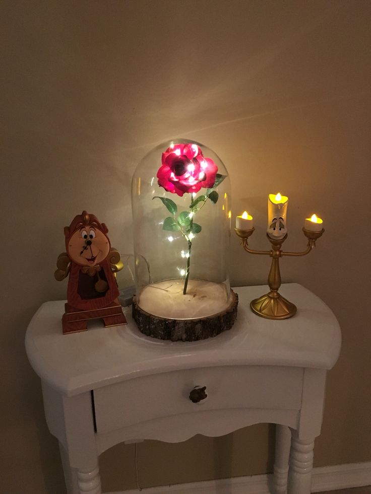 a white table topped with a glass dome filled with flowers and lite up candles