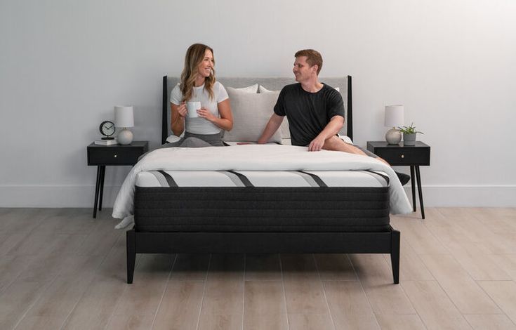 a man and woman sitting on top of a bed