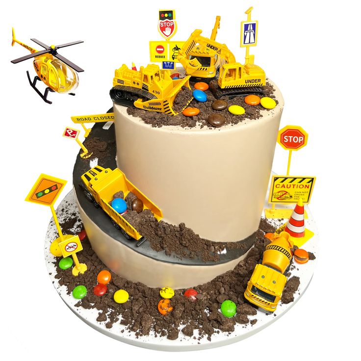 there is a cake that has construction vehicles on it and dirt around the cake,