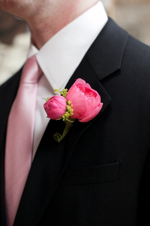 a man in a suit and pink tie with a boutonniere on his lapel