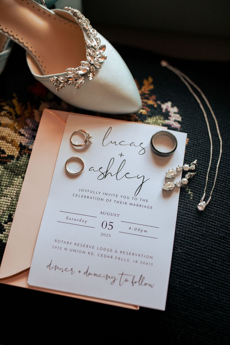 wedding details including rings and shoes on the floor next to a card that says love's sashley