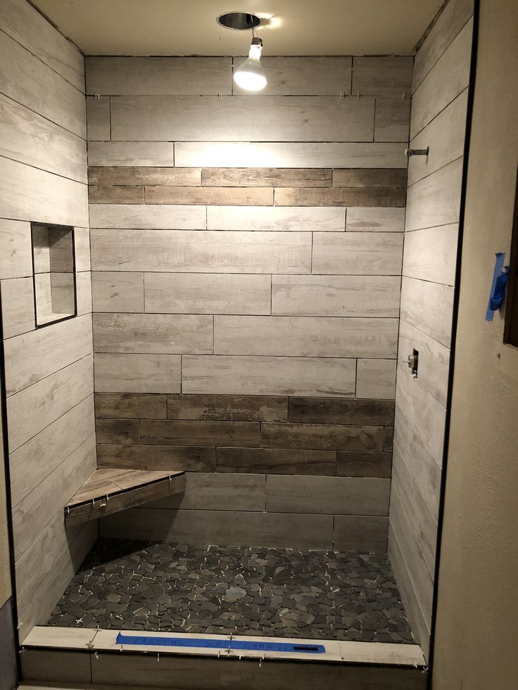 a walk in shower sitting next to a wall with rocks on the bottom and floor