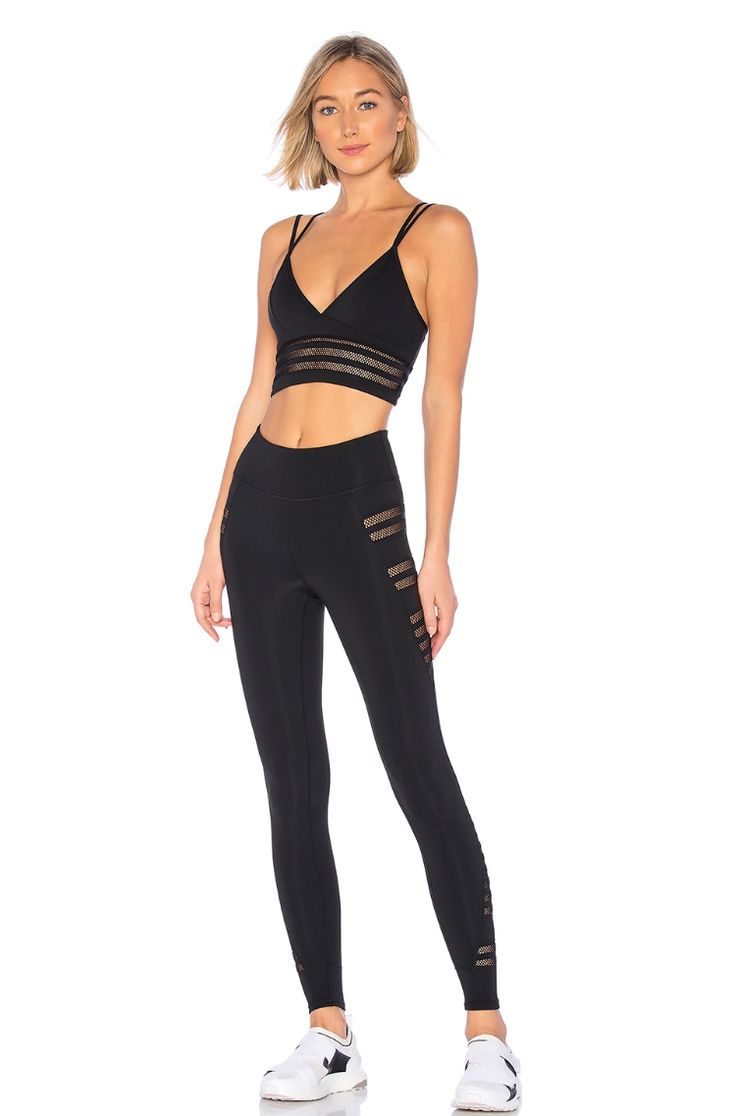 a woman in black sports bra top and leggings with mesh detailing on the side