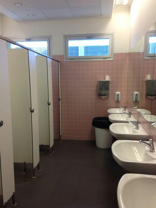 a bathroom with three sinks, two urinals and pink tiles on the walls