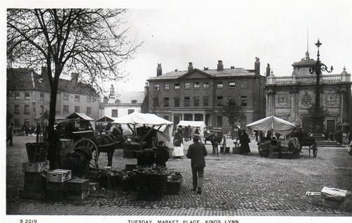 an old black and white photo of people walking around in the street with tents set up