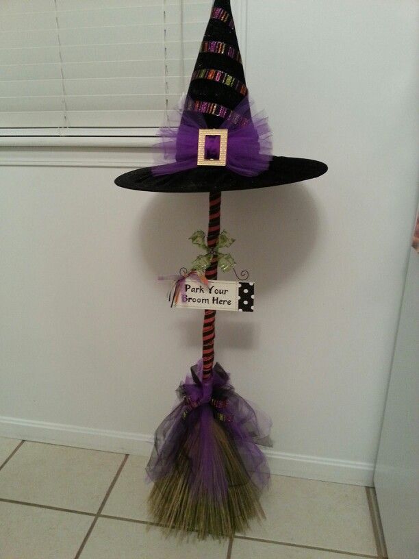 a witch hat on top of a broom in front of a wall with a sign