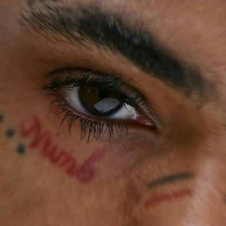 a man with tattoos on his face and eyeliners is looking at the camera