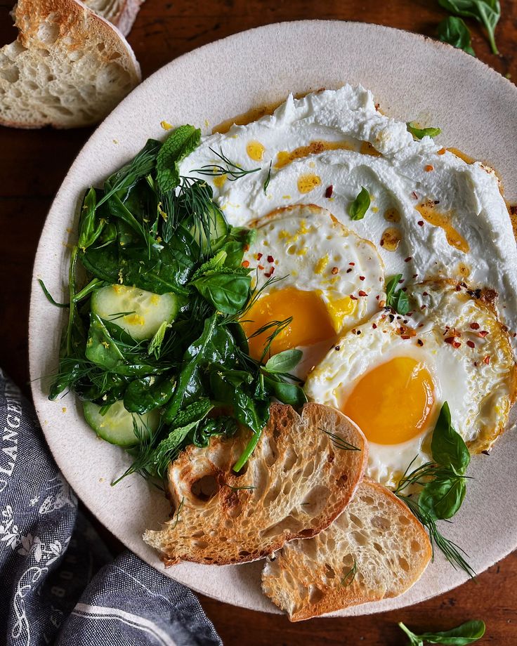 an egg, bread and spinach salad on a white plate