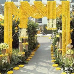 an outdoor ceremony with yellow and white flowers on the walkway, surrounded by greenery