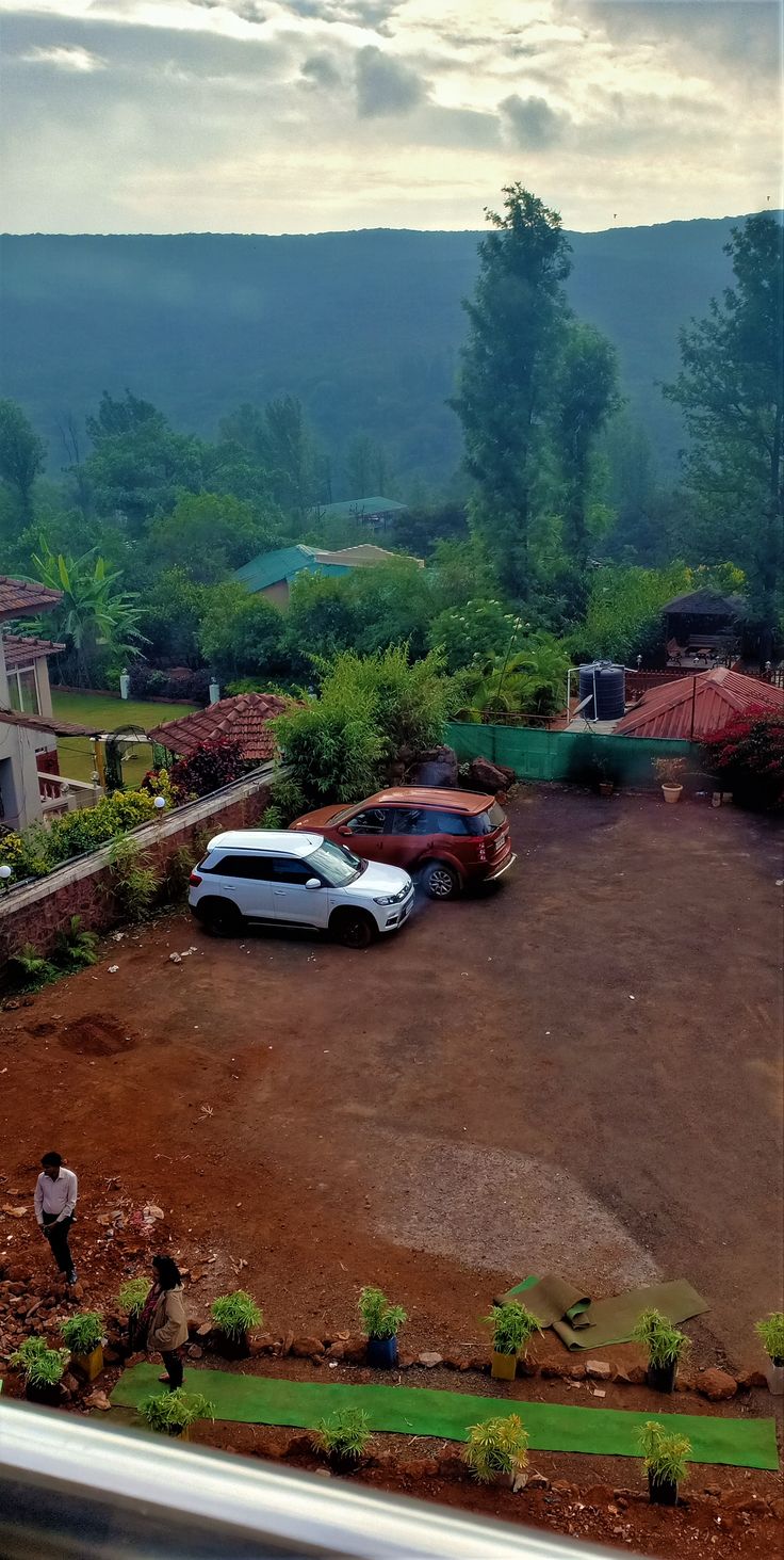 two cars parked in a lot with mountains in the background