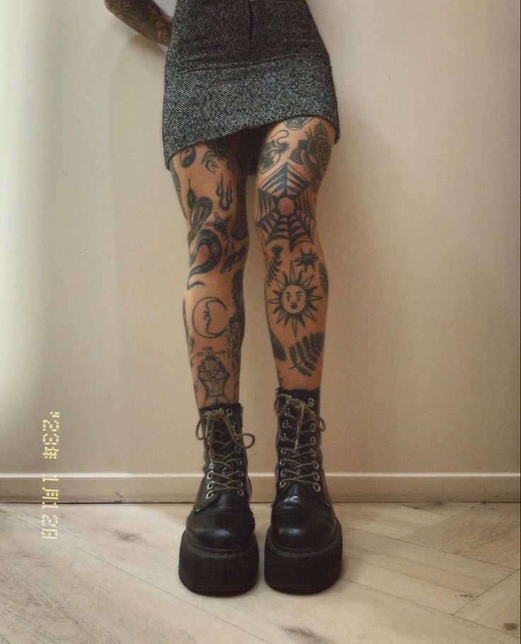 a woman with tattoos on her legs wearing boots