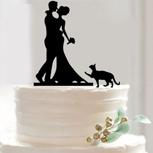 a wedding cake topper with a silhouette of a bride and groom holding hands next to a dog