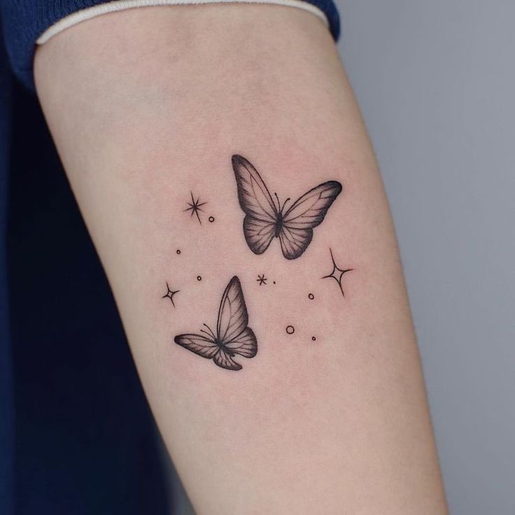 three butterflies tattoo on the right arm and left arm, with stars in the background