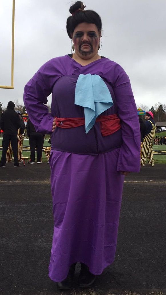 a woman dressed in purple is standing on the street