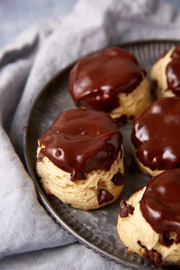 chocolate covered pastries sitting on top of a metal plate next to a gray napkin