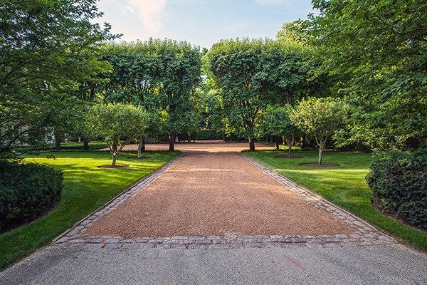 an empty driveway surrounded by trees and grass