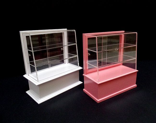 three different colored display cases sitting side by side on a black surface in front of a dark background