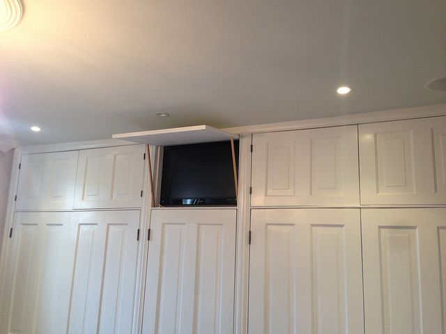 an empty room with white cupboards and a flat screen tv mounted on the wall