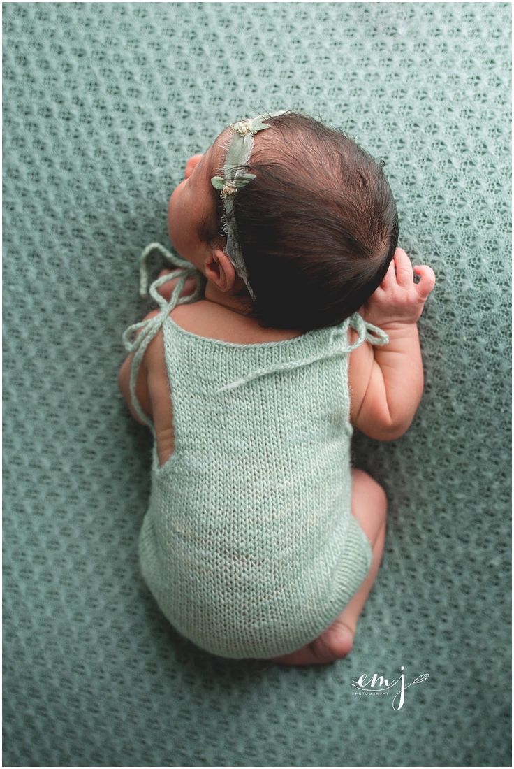 a baby laying on top of a green blanket