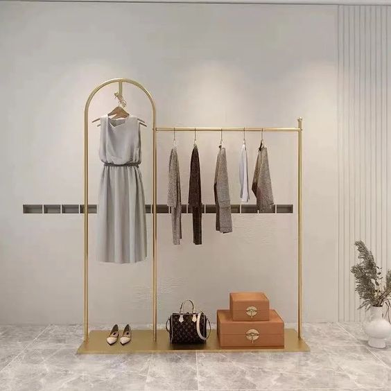 a clothing rack with clothes and purses on it in front of a white wall