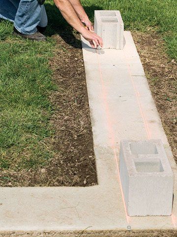 a man kneeling down next to a cement block on the ground with grass around it