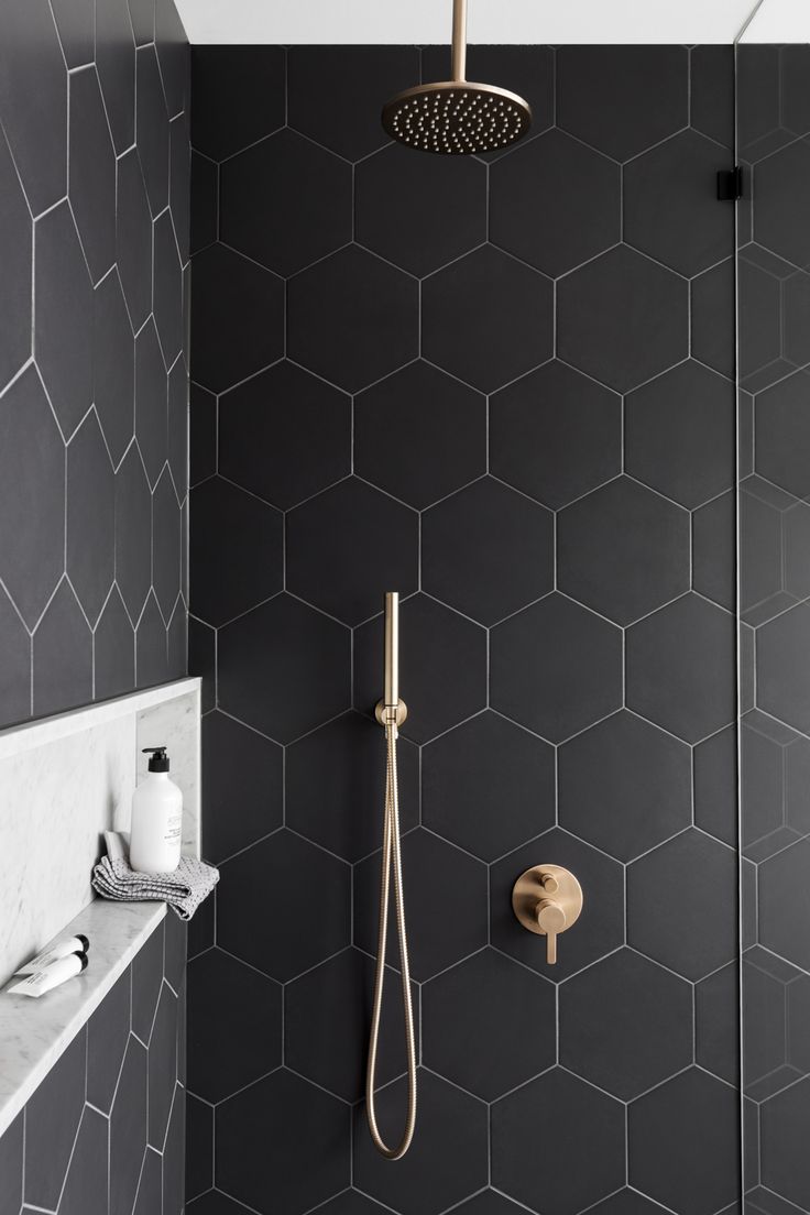 a bathroom with black tile and gold fixtures