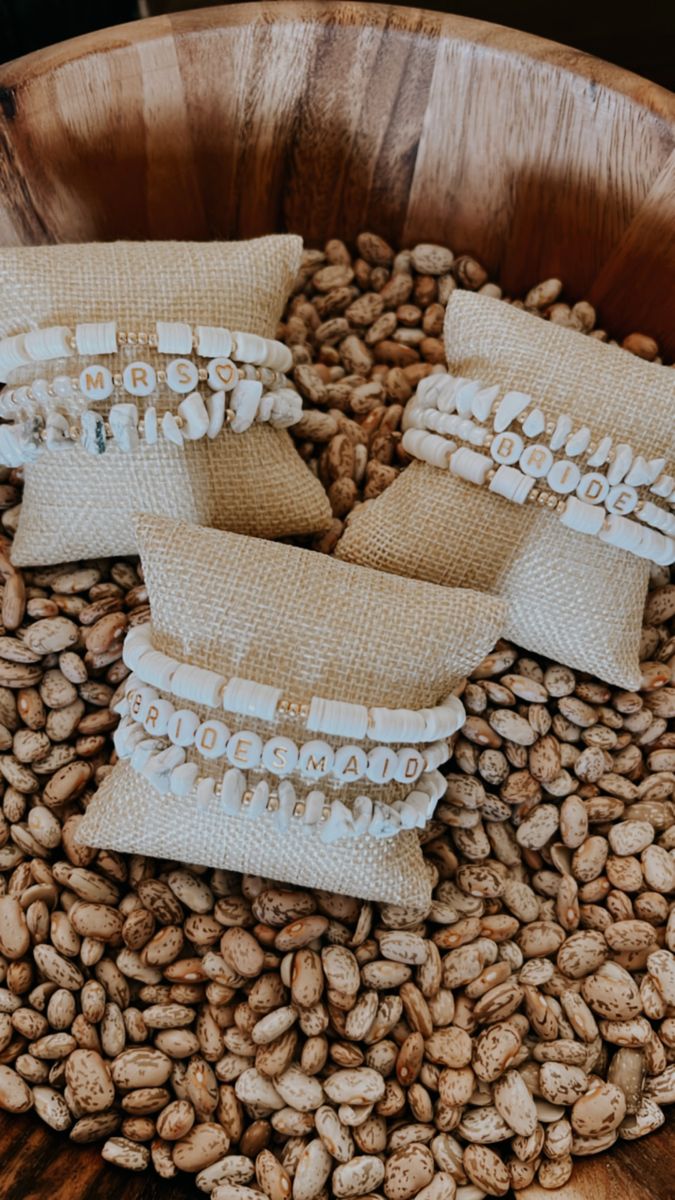 three burlap pillows sitting on top of some coffee beans in a wooden bowl