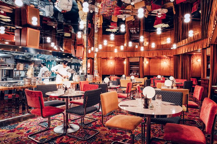 the interior of a restaurant with many tables and chairs, lights hanging from the ceiling