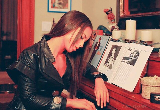 a woman sitting at a piano with her hands on the keyboard and an open book in front of her