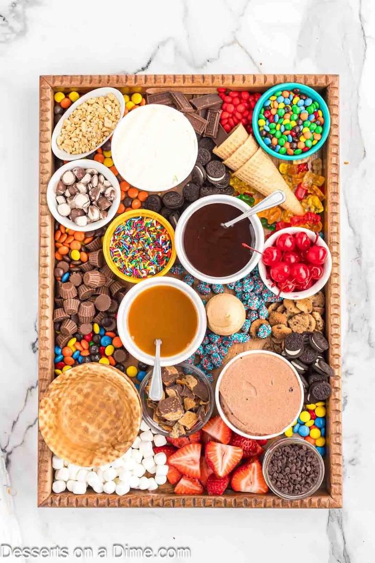 an assortment of desserts on a tray with chocolate, strawberries, ice cream and waffle cones