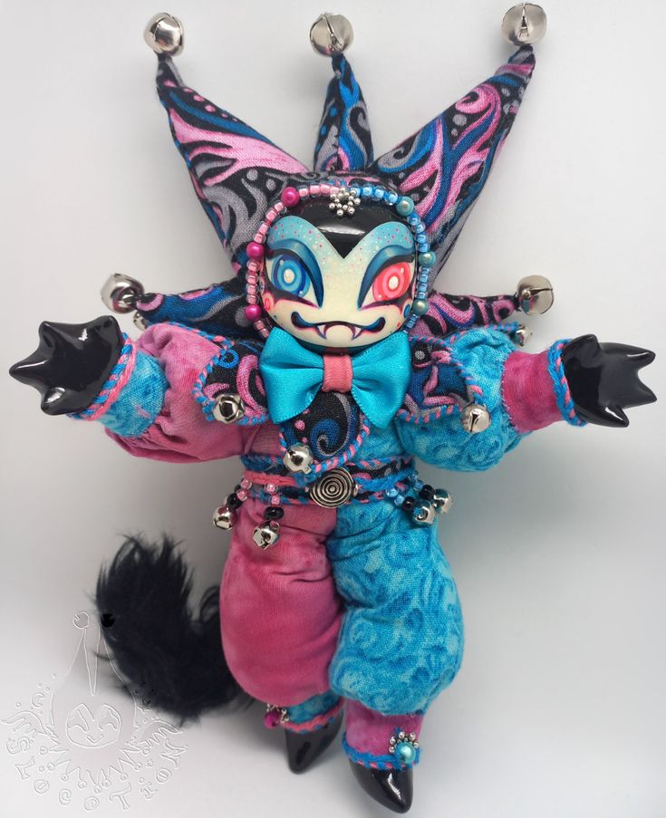 a stuffed animal is dressed up as a cat with blue and pink clothing on it's body