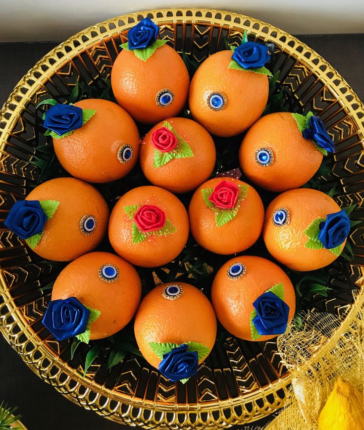 there are many oranges with blue flowers in the bowl on the table next to other decorations