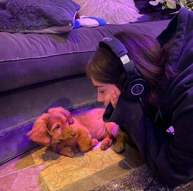 a woman wearing headphones petting a dog on the floor