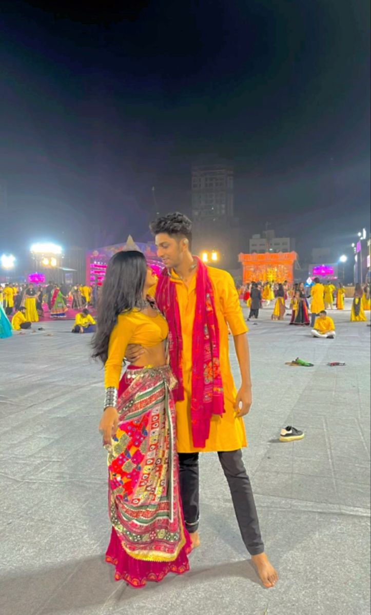 a man and woman standing next to each other in front of a crowd at night