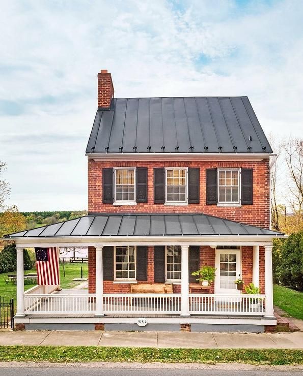 a red brick house with black shutters and an american flag on the porch