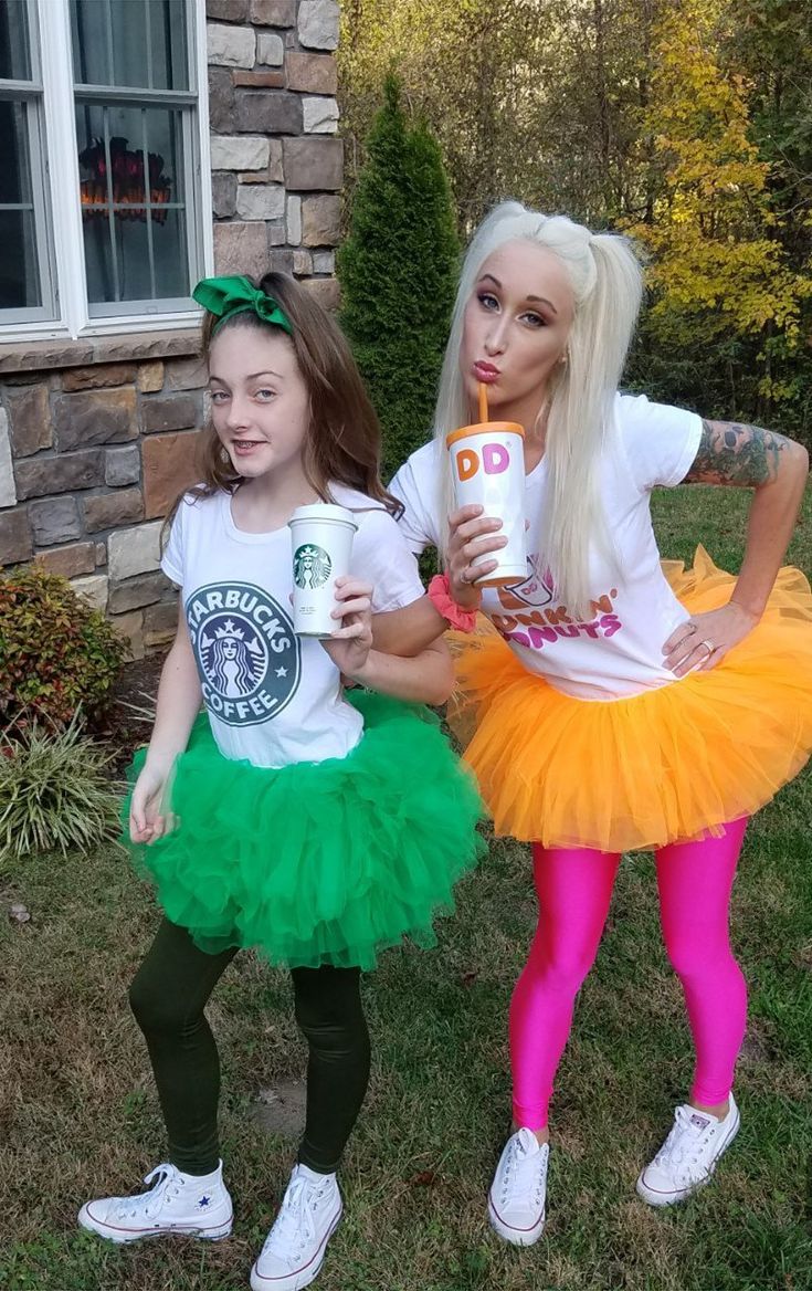 two girls dressed in costumes holding drinks and posing for the camera with one girl wearing a starbucks cup