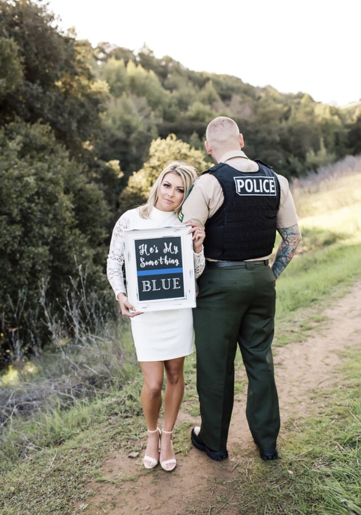 a man and woman standing on a dirt road holding a sign that says, he's not my blue