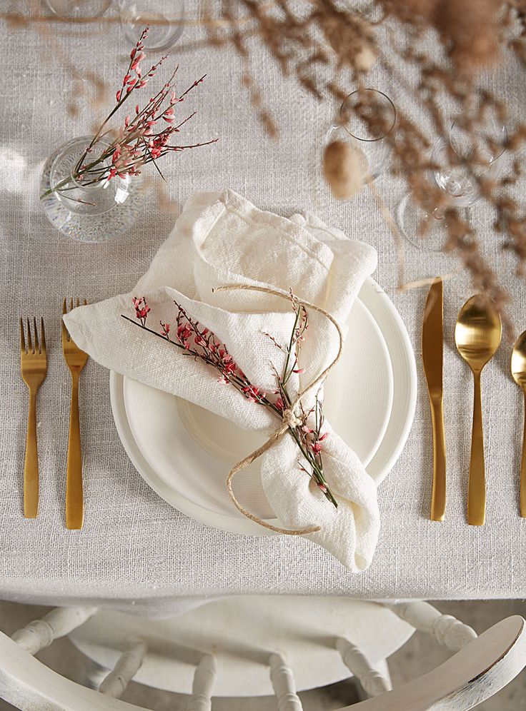 a place setting with white plates and gold cutlery, napkins and silverware