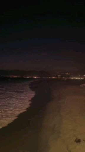 the beach is lit up at night time