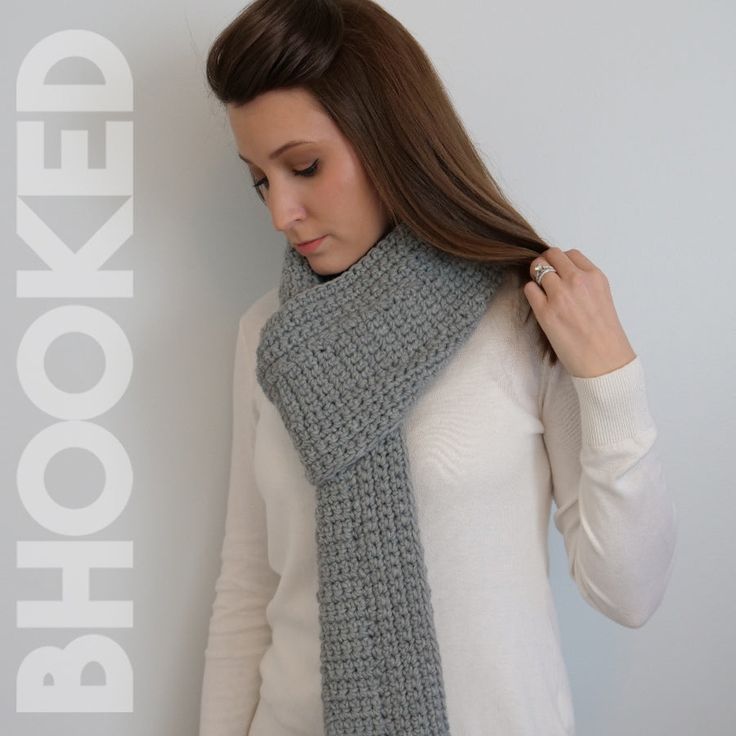 a woman wearing a gray crocheted scarf with the words hooked on it