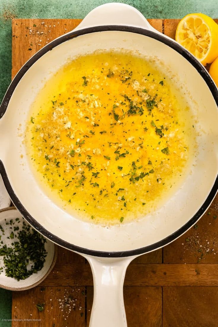 a bowl of soup with lemons and herbs