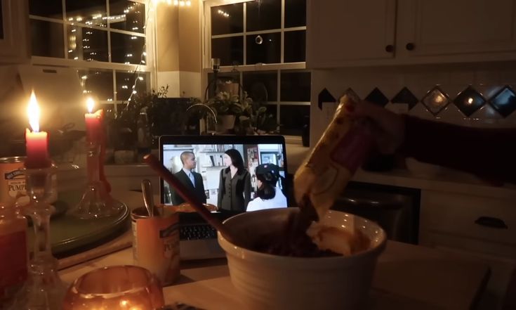 a table with candles and food on it in front of a computer screen that is turned on