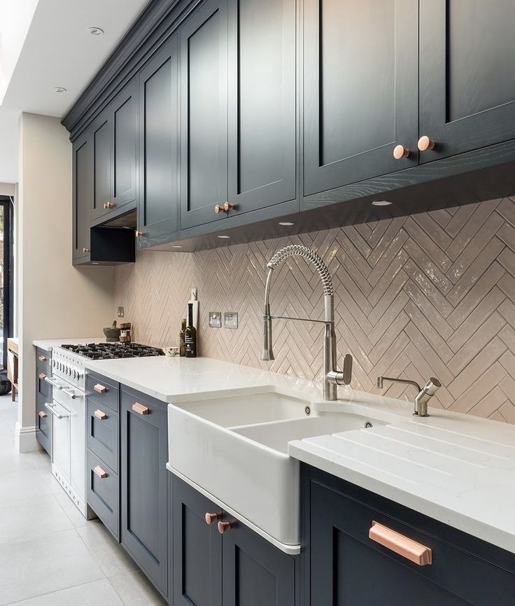 a kitchen with blue cabinets and white counter tops, copper pulls on the faucet