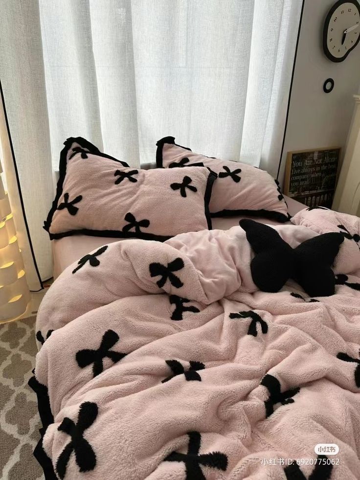 a bed covered in pink and black flannel with bows on the comforter