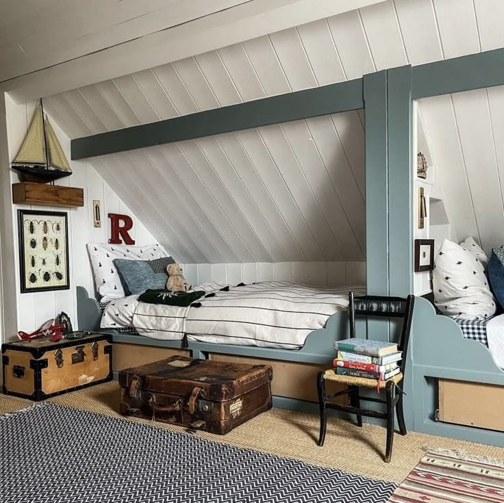 an attic bedroom with twin beds and suitcases on the floor