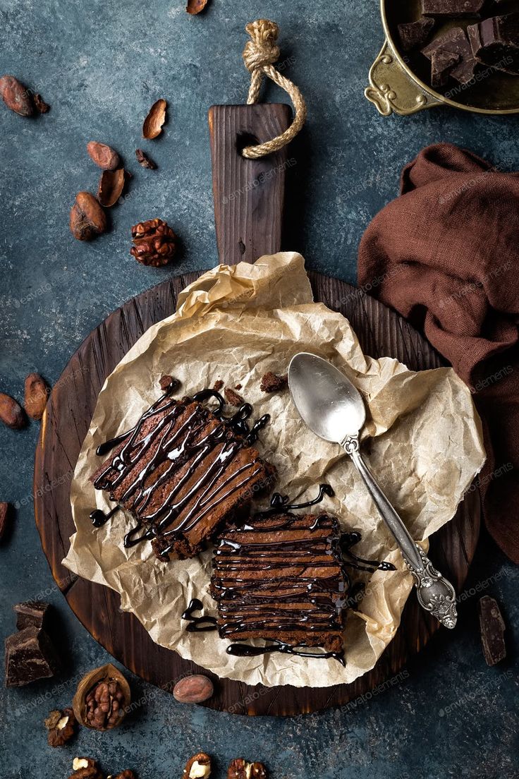 a plate with some chocolate cake and nuts on top of it next to a spoon