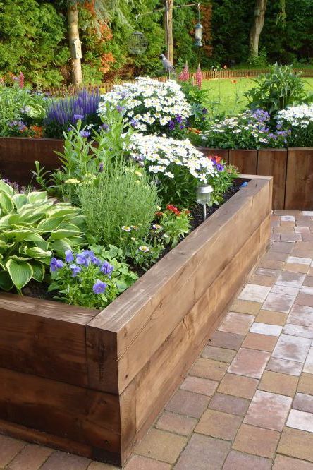 a wooden planter filled with lots of different types of flowers and plants in it