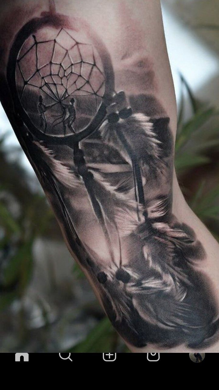 an arm tattoo with a dream catcher and feathers on the inside of it, in black and white